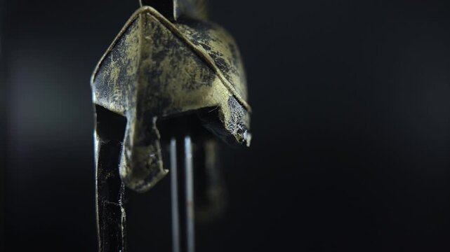 Ancient bronze gladiator helmet on rotating stand, cinematic macro shot with reflections