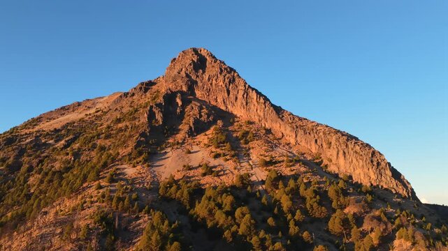Rocky summit of Nevado de Colima (Zapot&eacute;petl) illuminated by warm golden hour light with sparse vegetation across steep slopes in Jalisco, Mexico
