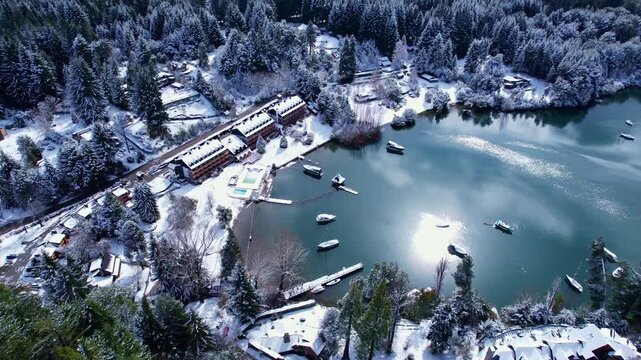 Forward drone dolly in shot with a high angle camera view over a luxury resort and houses covered in fresh snow in Puerto Manzano, Villa La Angostura, Patagonia Argentina.