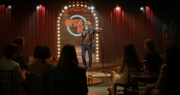 Male Comedian Opens a Stand-up Set Onstage, Delivering Jokes Into a Microphone Seated Audience Applauds and Laughs at the Live Comedy Performance. Beginning of the Funny Show at the Bar