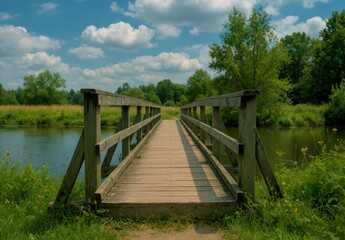 Obraz premium Peaceful wooden footbridge over a calm river in a green landscape