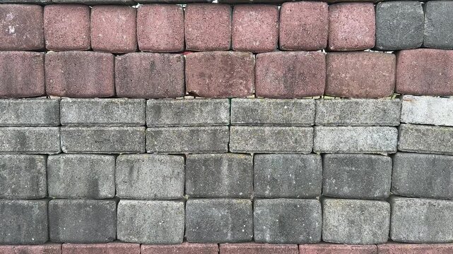 Top view paving stone samples display, close-up textured red and gray pavers arranged in grid on sales stand, showroom background