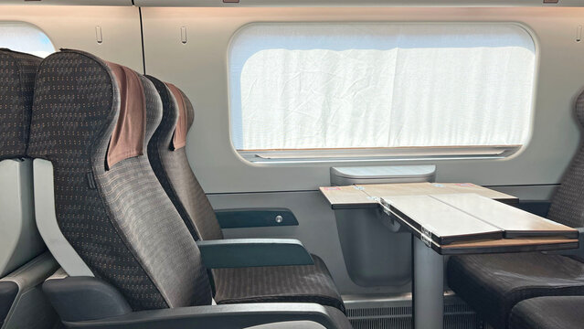 Empty comfortable passenger seats with brown headrests and a folding table inside a modern high speed train. Travel, comfort, and commuting.