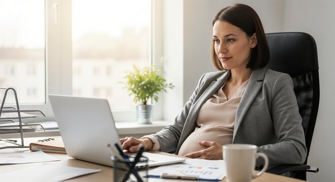 Pregnant manager working at desk using laptop with coffee in modern office. Expectant manager engaged in business tasks with documents on table, exuding professionalism in corporate environment.