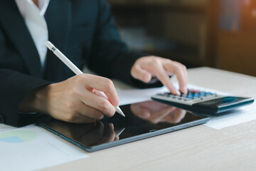 Fototapeta premium Business professional using tablet stylus and calculator for financial analysis, budgeting and accounting work.