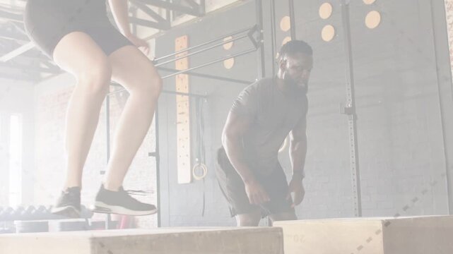 Woman and man starting low squat on plyo boxes, synchronizing explosive jumping for fitness power