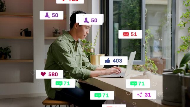 Vertical video: Typing man in green shirt checking laptop and tablet at window while alerts rising