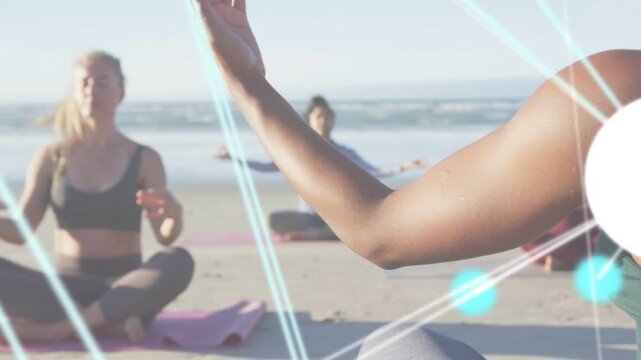 Instructor raising arms and causing blue lines and nodes while guiding beach yoga class into mudra
