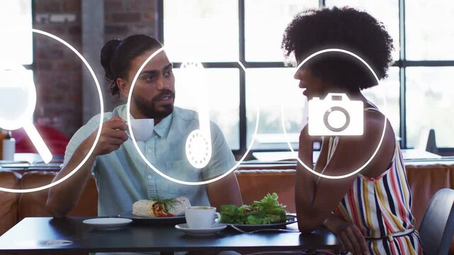 Two diners discussing app features at cafe, sparking animated icons moving over faces and table