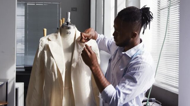 Tailor placing jacket on size 10 form, smoothing as golden overlay appearing, pinning lapel shaping