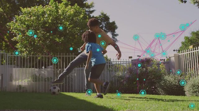 Child pressing, adult dribbling soccer ball on lawn with cyan hexagons and pink lines for sports