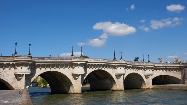 Pont Neuf in Paris spanning Seine under clear blue spring sky with soft clouds