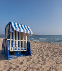 Fototapeta premium Strandkorb on sandy Rugen beach with blue striped canopy and calm Baltic Sea