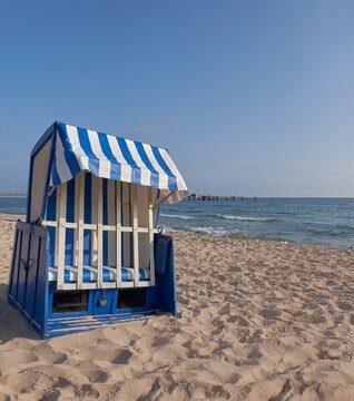 Strandkorb on sandy Rugen beach with blue striped canopy and calm Baltic Sea