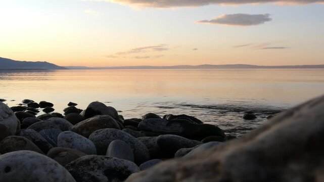 Sunset on Lake Baikal in Russian Siberia on a chilly autumn evening. The orange sky is reflected in the calm surface of the lake.