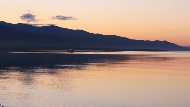 Sunset on Lake Baikal in Russian Siberia on a chilly autumn evening. The orange sky is reflected in the calm surface of the lake.