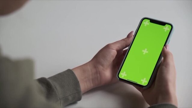 Close-up of Woman Hands Using Smartphone with Green Screen and Tracking Markers on White Background