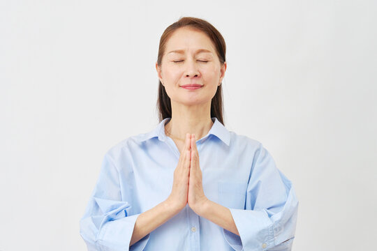 白背景で祈る高齢女性