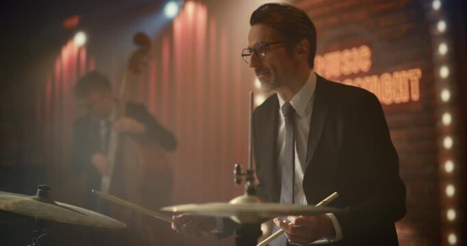 Portrait of a Male Drummer in Glasses Playing Jazz Music Live on Stage as the Band Performs a Song at a Stylish Bar Concert Event, Keeping Rhythm for the Audience Beside. Cinematic Camera Movement