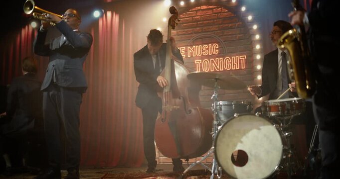 Live Jazz Band Musicians Playing an Energetic Song on a Bar Concert Stage, as a Black Male Trumpeter, Male Bassist, and Drummer Perform for the Audience at a Stylish Night Event.