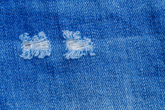 Repairing torn denim fabric in blue jeans at home during the day