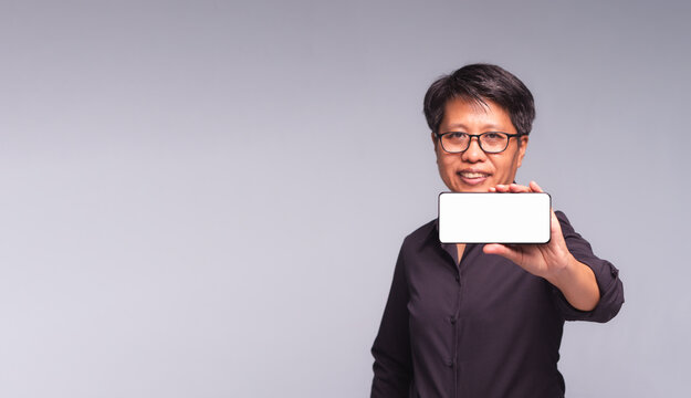 Short-haired professional showing blank smartphone screen in studio
