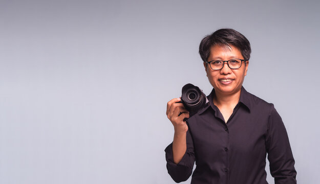Short-haired woman holding camera in studio portrait
