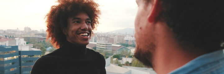 Obraz premium Close-up of young mans talking, in the background on the terrace his friends. Panoramic. Panoramic