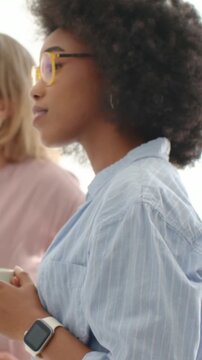 Vertical video: Pointing senior urging junior in blue with mug, shifting gaze in studio, copy space