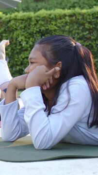 Vertical video: Watching youth in light top flexing left elbow on yard mat as friend leg sliding in