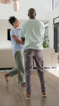 Vertical video: Entering couple walking through glass door, twirling and hugging, reuniting at home