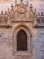 Obraz premium Ornate Gothic Stone Window With Coat of Arms and Intricate Carvings on Historic Royal Chapel of Granada