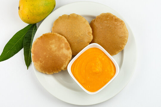 Indian festival lunch or Dinner Mango ras and Puri serve in plate isolated on white background 