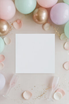 Square 5x5 greeting card mockup on pastel background. Aesthetic celebration flat lay with colorful balloons, rose petals, gold glitter, and champagne glasses. Minimalist festive stationery template.