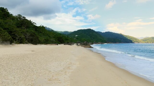 Empty Cepilho Beach with white sand, rocks and turquoise ocean waves in Trindade, Paraty, Brazil. Push in camera movement at eye level