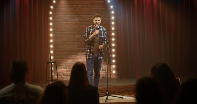 Male Standup Comedian Delivers a Lively Comedy Club Set, Telling Jokes Into a Mic, Pacing the Stage, Using Hand Gestures, and Connecting With the Crowd During a Live Open Mic Event.