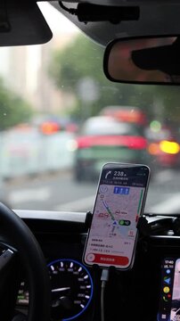 Navigation app on smartphone mounted in car dashboard driving through rainy city street in China GPS route guidance traffic travel technology video