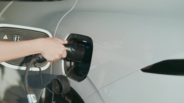 4K slow motion person charging electric car at home.