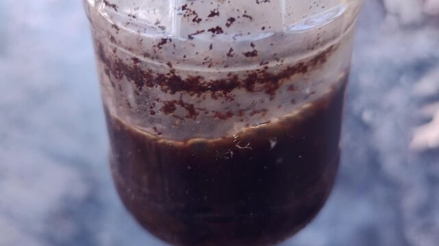 Making coffee in a glass jar over a campfire, outdoor survival lifehack