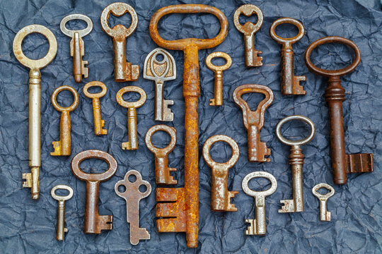 Many old keys arranged on a dark surface with different shapes and sizes in a collection