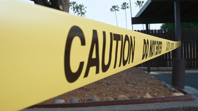 Yellow caution tape do not enter along fenced unsafe restricted zone daytime shows restricted access area safety and perimeter control in outdoor environment
