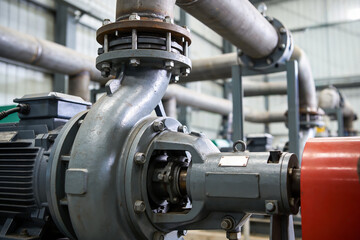 Obraz premium Industrial worker in gloves tightening bolts on a large pump with a wrench in a factory setting