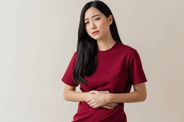 Obraz premium Young woman holding stomach in discomfort in studio
