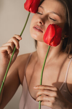 A portrait of an attractive young woman surrounded by tulips near her face. Symbolic of femininity, the female cycle, calm and stress management, and meditation.