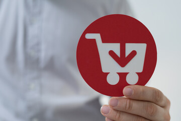 Person's hand holds a red circle with a shopping cart and download icon. © vegefox.com
