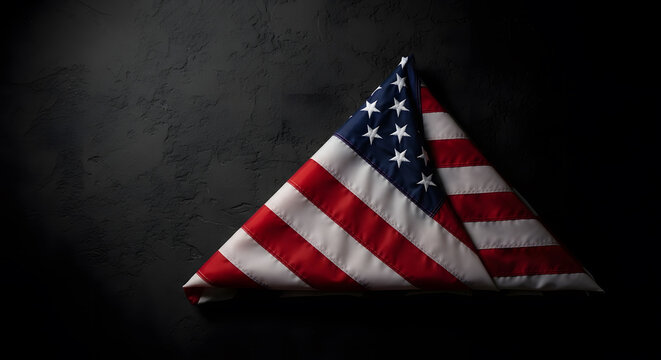 American flag folded into triangle shape against dark textured background with dramatic lighting.