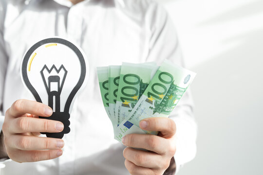 Person holding lightbulb and euro banknotes symbolizing financial gain from innovation and good idea