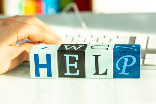 A hand typing on a keyboard with blocks spelling out HELP.