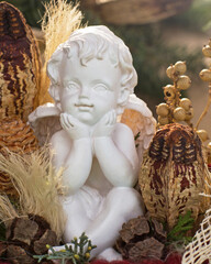 Obraz premium Statue of a child angel surrounded by plants and natural decorations in a cozy setting