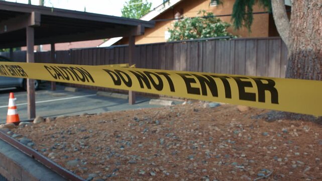 Yellow caution tape do not enter blocking fenced unsafe parking area daytime shows restricted access area safety and perimeter control in outdoor environment
